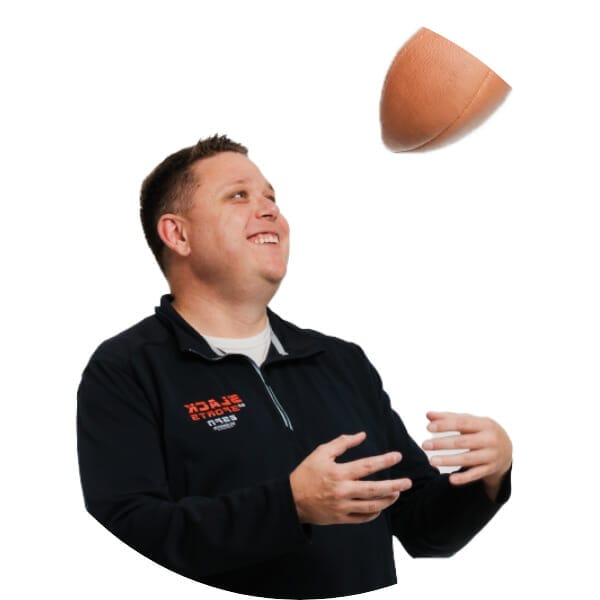 Randy in a black long sleeve shirt tossing a football in the air