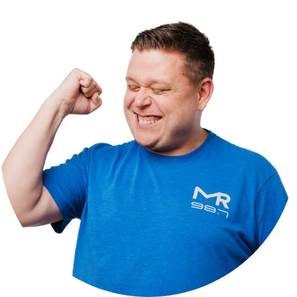 Randy in a blue shirt with his eyes closed and his fist clenched above his shoulder in a display of conquer